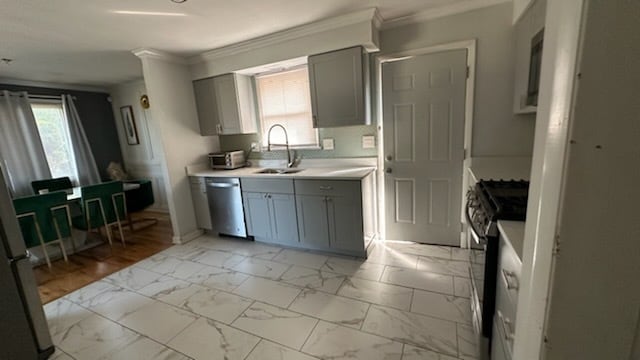 kitchen with ornamental molding, gray cabinetry, stainless steel appliances, and sink