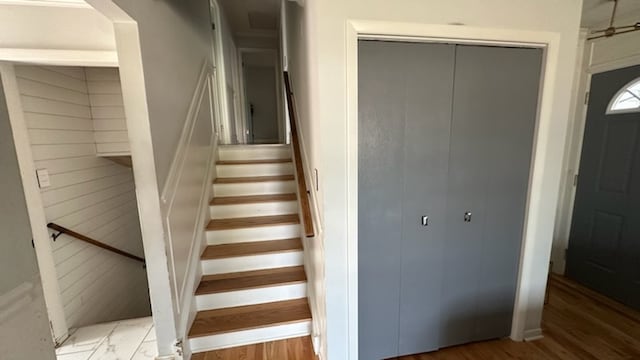 stairway featuring wood-type flooring and wooden walls