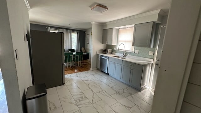 kitchen with gray cabinets, crown molding, light hardwood / wood-style flooring, stainless steel appliances, and sink