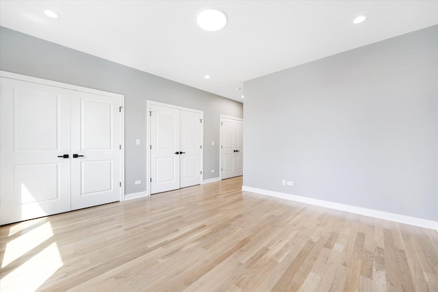 unfurnished bedroom featuring light hardwood / wood-style flooring and two closets