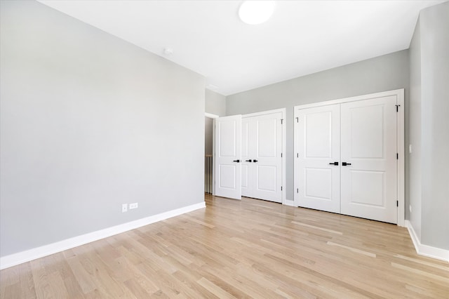 unfurnished bedroom with two closets and light wood-type flooring