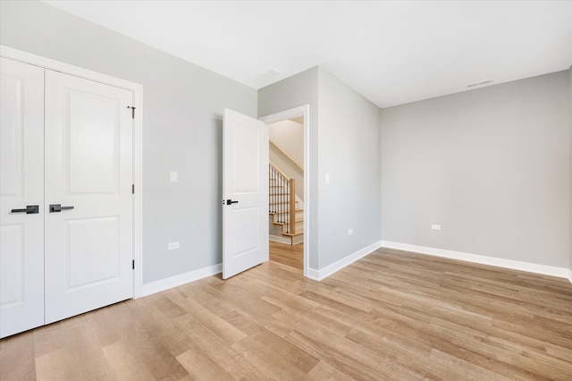 unfurnished bedroom with light hardwood / wood-style flooring and a closet