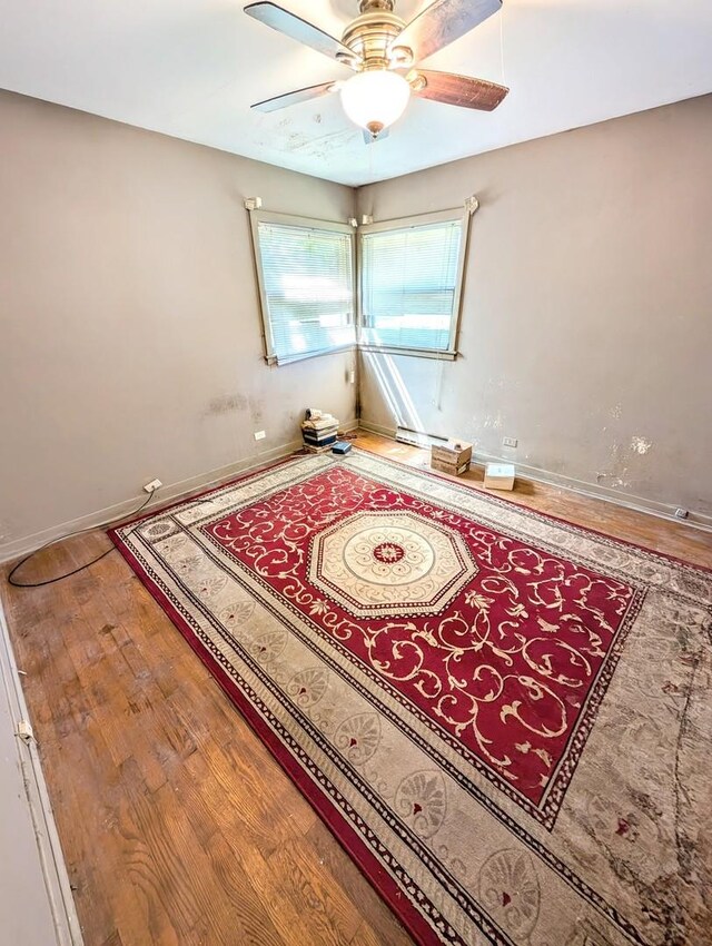 interior space featuring ceiling fan, baseboard heating, and wood-type flooring