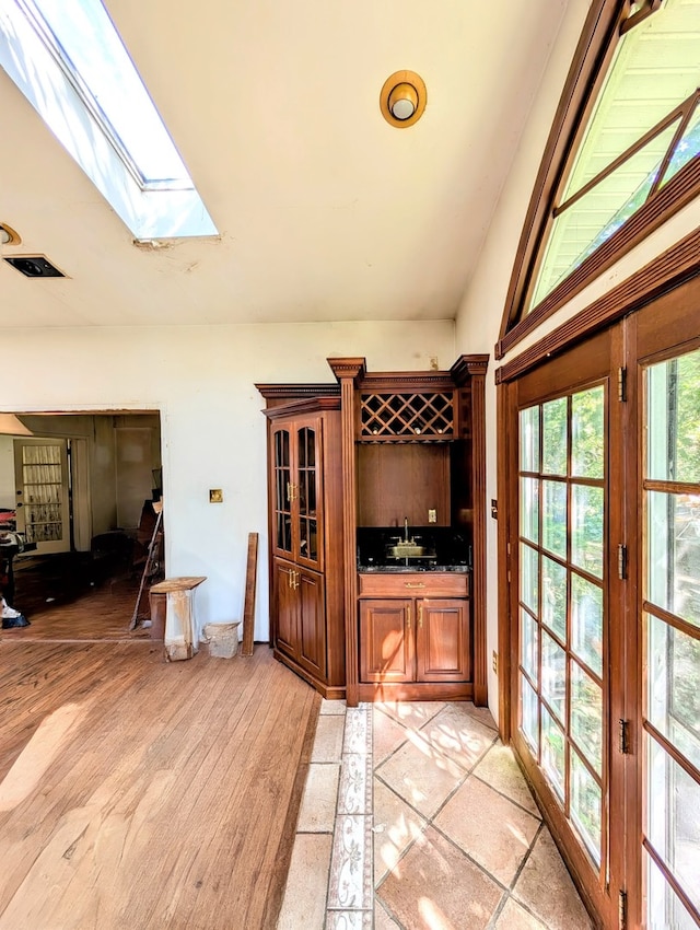 interior space with sink, light wood-type flooring, and lofted ceiling with skylight