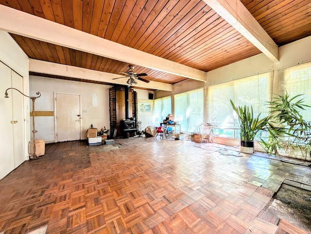 interior space featuring wooden ceiling, a wood stove, beam ceiling, and ceiling fan