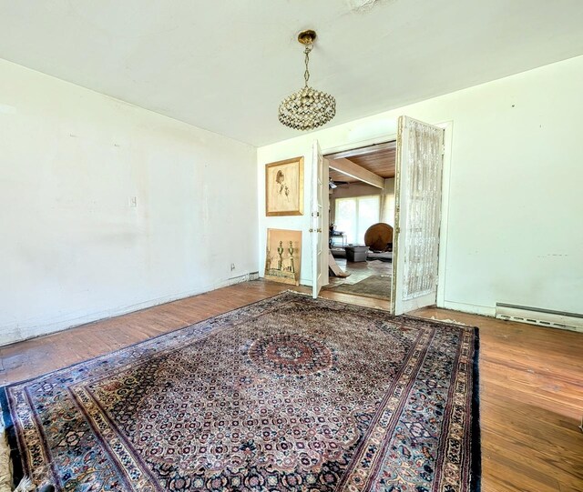 spare room featuring baseboard heating and hardwood / wood-style flooring