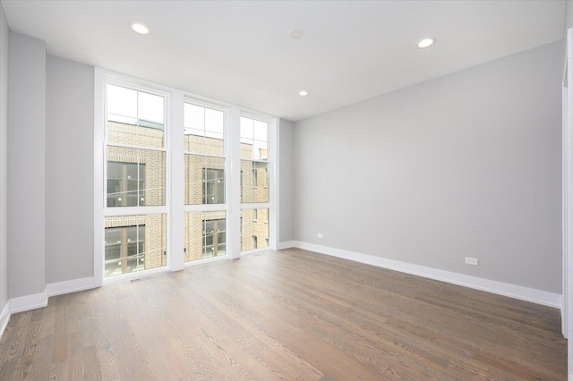 empty room featuring recessed lighting, baseboards, and wood finished floors