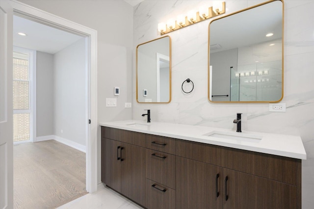 full bath with double vanity, wood finished floors, backsplash, and a sink