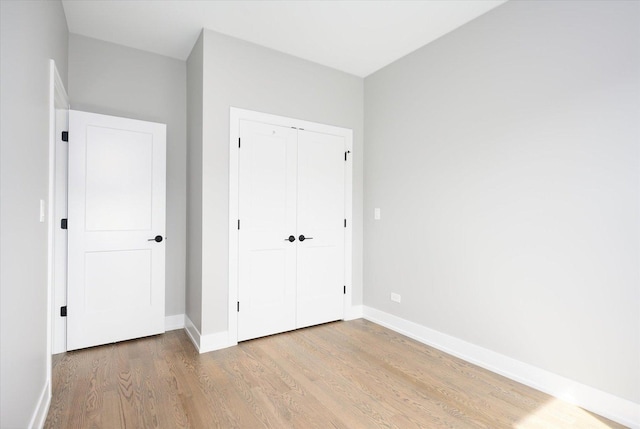 unfurnished bedroom with a closet, wood finished floors, and baseboards