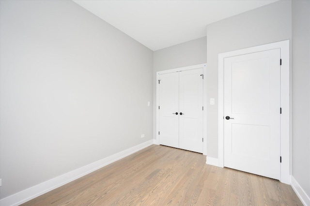 unfurnished bedroom with light wood-style floors, a closet, and baseboards