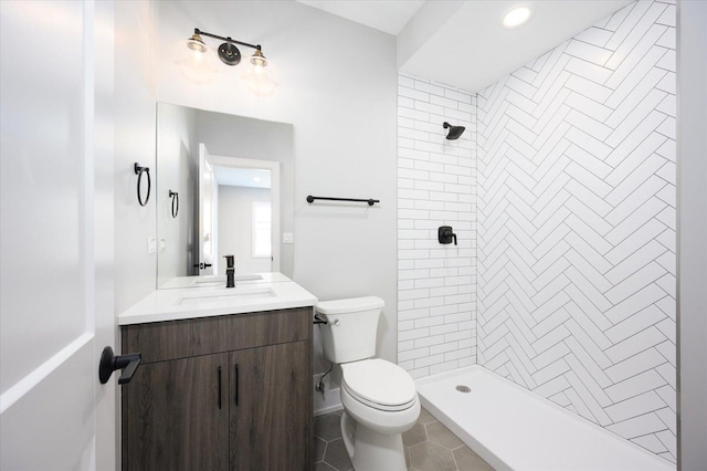 full bath featuring tiled shower, vanity, toilet, and tile patterned floors