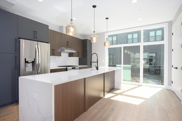 kitchen featuring stainless steel appliances, plenty of natural light, a sink, and under cabinet range hood