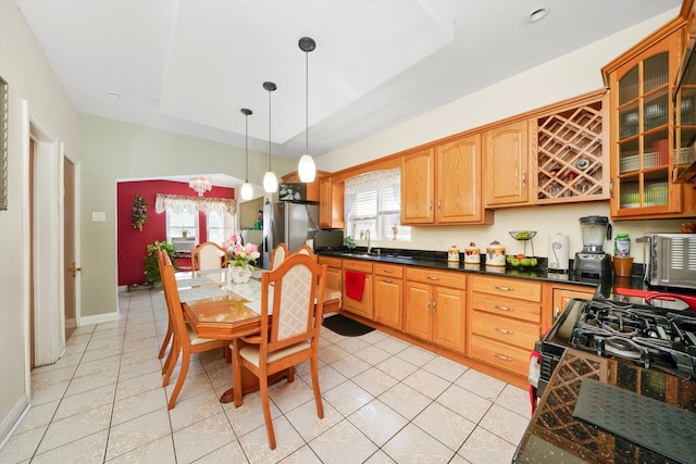 kitchen featuring dark countertops, glass insert cabinets, black gas range, pendant lighting, and light tile patterned floors