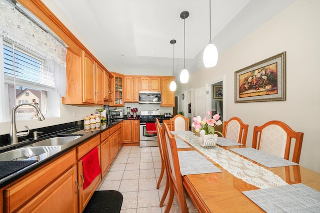 kitchen with dark countertops, glass insert cabinets, light tile patterned floors, stainless steel appliances, and a sink