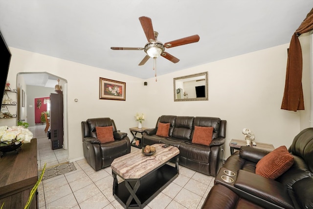 living room with light tile patterned floors, arched walkways, and ceiling fan