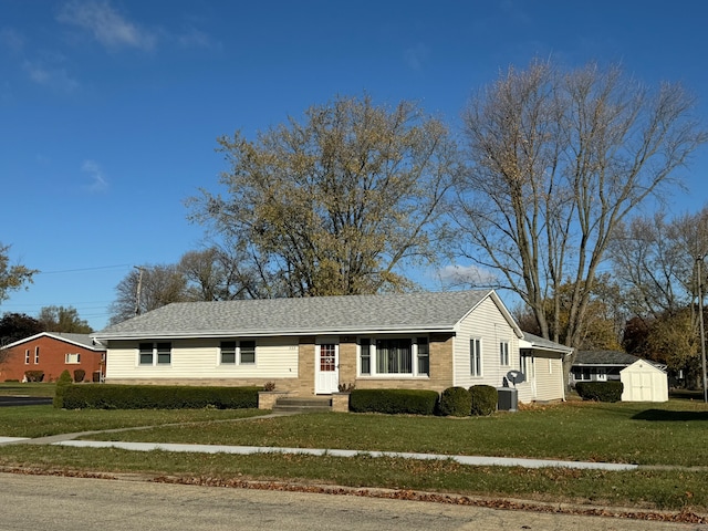 view of front facade featuring a storage unit, cooling unit, and a front lawn