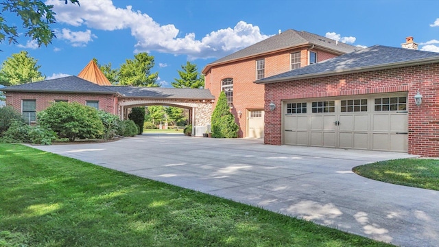 4703 W Kirby Ave, Champaign, IL 61822 - view of side of home featuring concrete driveway, brick siding, a garage, a yard, and a chimney