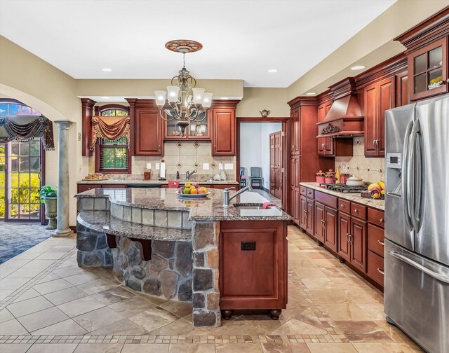 kitchen featuring backsplash, sink, appliances with stainless steel finishes, and custom range hood