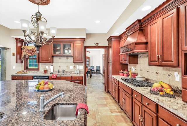 kitchen featuring custom exhaust hood, stone countertops, decorative light fixtures, an inviting chandelier, and appliances with stainless steel finishes