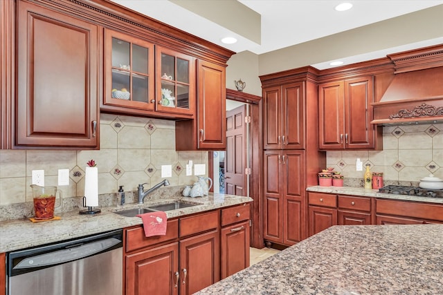 kitchen featuring stainless steel appliances, light stone counters, sink, decorative backsplash, and custom range hood