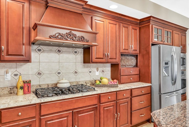 4703 W Kirby Ave, Champaign, IL 61822 - kitchen with appliances with stainless steel finishes, custom range hood, decorative backsplash, glass insert cabinets, and light stone counters