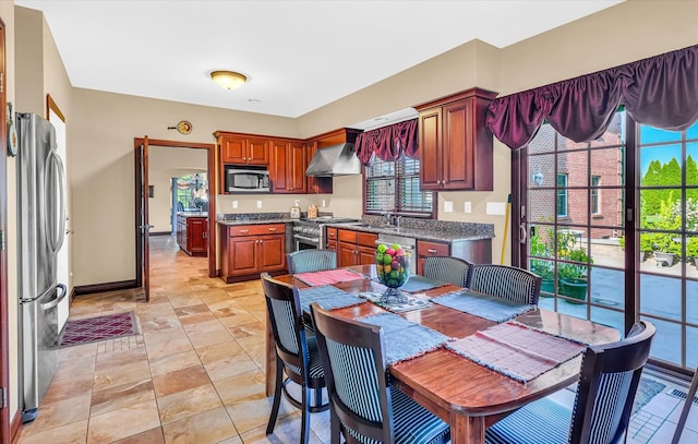 kitchen featuring plenty of natural light, stainless steel appliances, sink, and wall chimney range hood