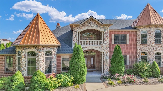 4703 W Kirby Ave, Champaign, IL 61822 - view of front of property featuring a balcony, roof with shingles, stone siding, and a chimney