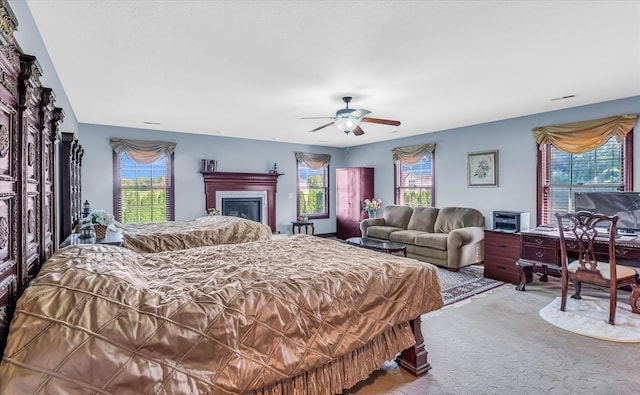 carpeted bedroom featuring multiple windows and ceiling fan