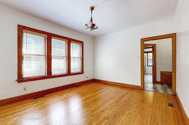 empty room featuring light wood-type flooring and crown molding