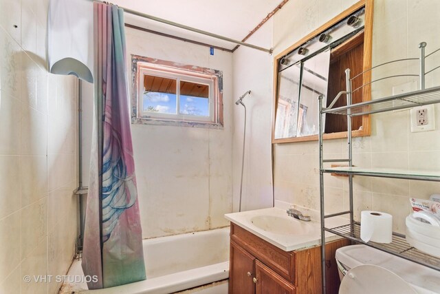 full bathroom with toilet, tile walls, shower / bathtub combination with curtain, and vanity