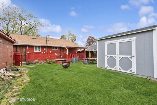 view of yard with a storage shed, an outdoor structure, central AC, and a wooden deck