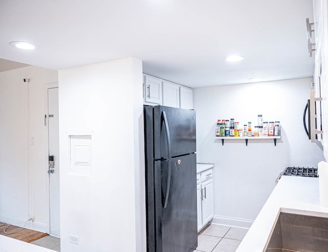 kitchen with black fridge, white cabinets, and light hardwood / wood-style floors