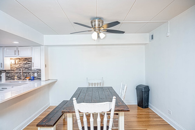 unfurnished dining area with light wood-type flooring, sink, and ceiling fan