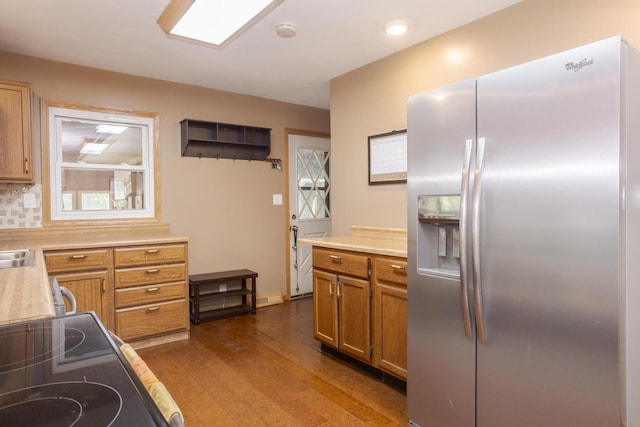 kitchen featuring light countertops, electric range oven, brown cabinets, dark wood-style floors, and stainless steel fridge