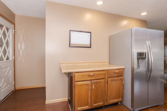 kitchen featuring recessed lighting, brown cabinetry, stainless steel fridge with ice dispenser, baseboards, and light countertops