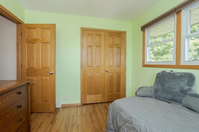 bedroom featuring visible vents, baseboards, light wood-style floors, and a closet