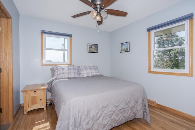 bedroom featuring visible vents, ceiling fan, baseboards, and wood finished floors