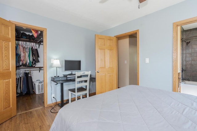 bedroom featuring wood finished floors, baseboards, a spacious closet, a closet, and ensuite bathroom