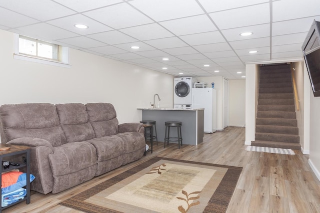 living area with stairway, recessed lighting, light wood-style floors, a paneled ceiling, and stacked washer / dryer