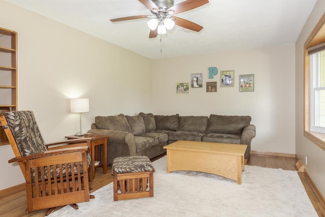 living area featuring baseboards, a ceiling fan, and wood finished floors