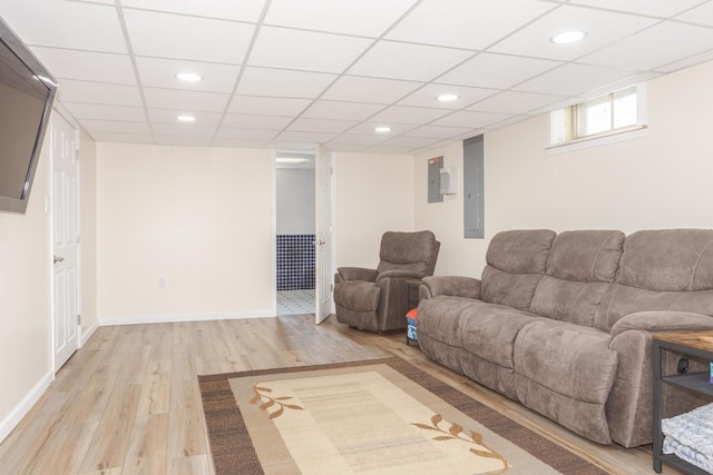 living room featuring electric panel, a drop ceiling, wood finished floors, recessed lighting, and baseboards