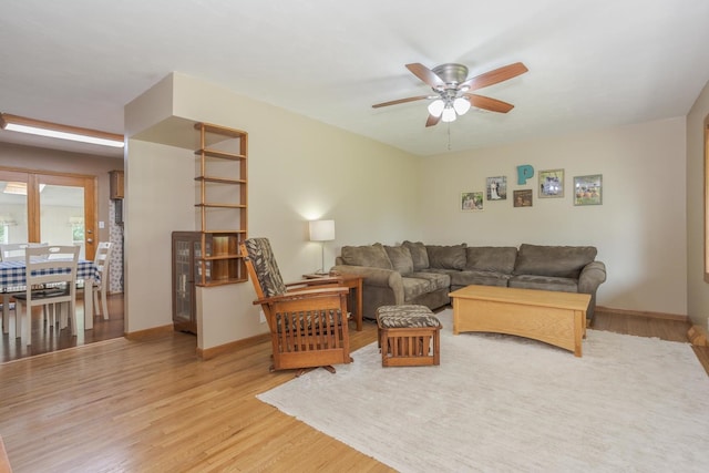 living room with light wood-type flooring, baseboards, and a ceiling fan