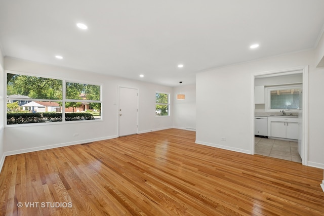 unfurnished room with light wood-type flooring, ornamental molding, and sink