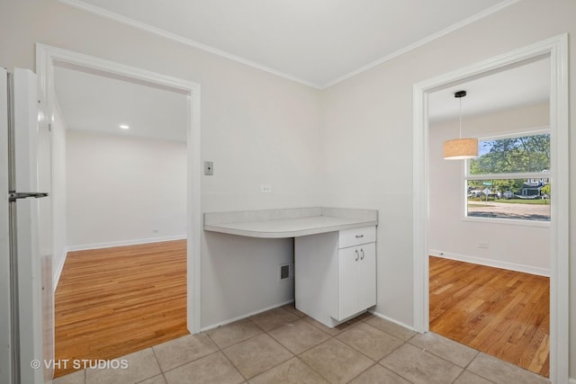 kitchen with crown molding, light countertops, white cabinetry, and light tile patterned floors