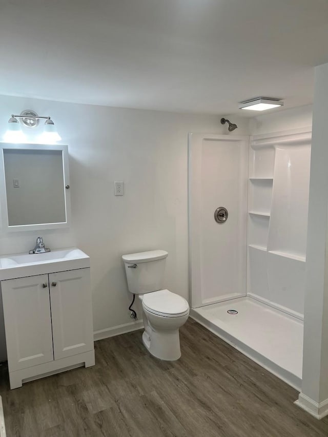 full bath with vanity, a walk in shower, wood finished floors, and toilet