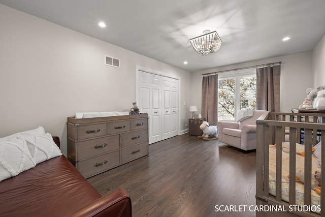 bedroom featuring dark wood-type flooring, an inviting chandelier, and a closet