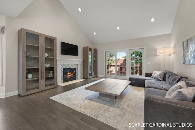 living room featuring dark hardwood / wood-style flooring, high vaulted ceiling, and a tile fireplace