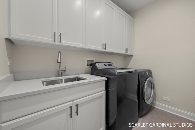 clothes washing area featuring cabinets, washer and dryer, and sink