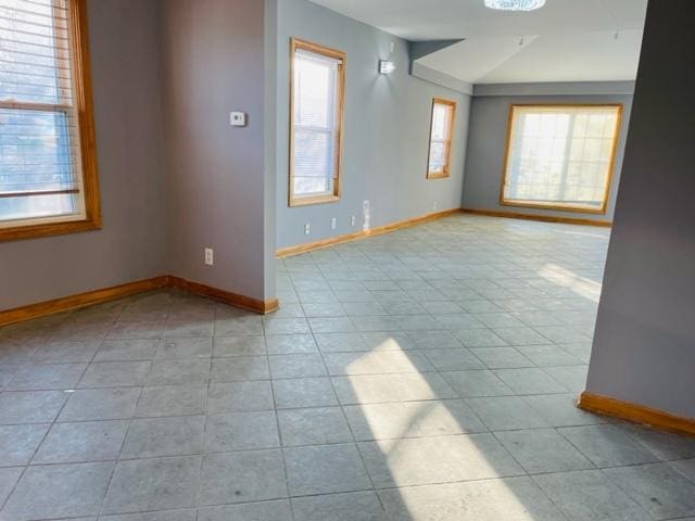 spare room with light tile patterned flooring and vaulted ceiling