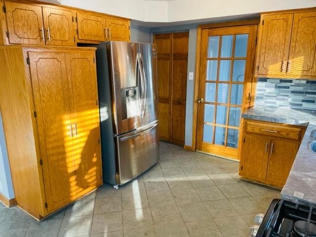 kitchen with backsplash, stainless steel fridge, range with electric stovetop, and light tile patterned flooring